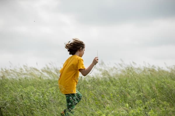 Boy running through a field of wildflowers